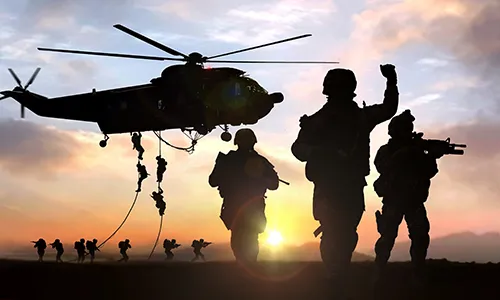 Silhouette of soldiers and a helicopter at sunset